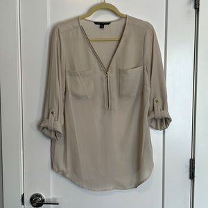 Flowy cream blouse with gold zipper detail.